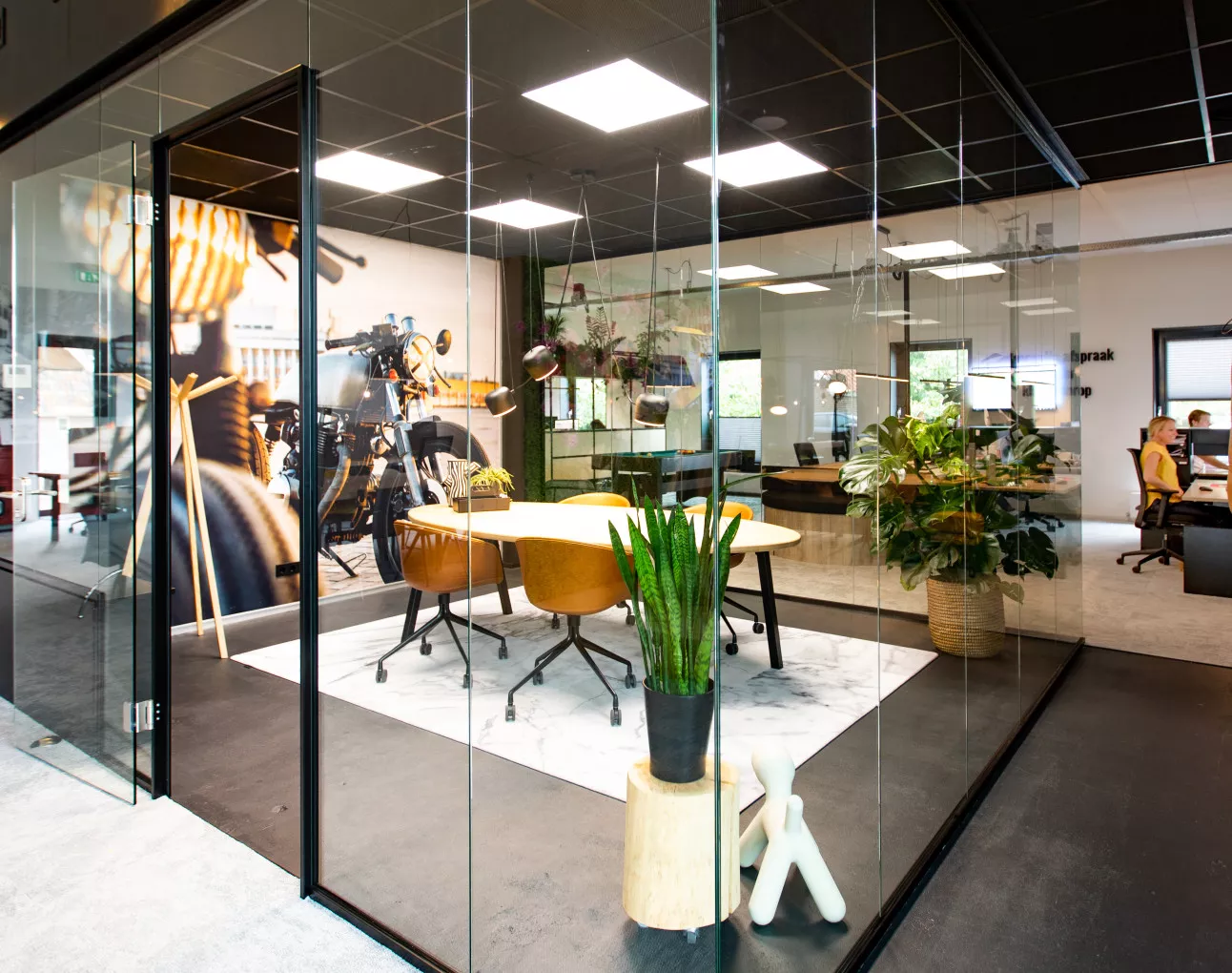 Glazen overlegruimte met ovale tafel en okergele stoelen in de showroom van Kantoormeubelen.pro in Enschede